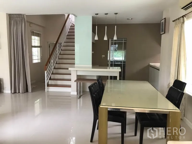 独立式住宅 出租在Khlong Sam Wa, Bangkok - 餐桌区面向楼梯，吊灯与备餐台相连。