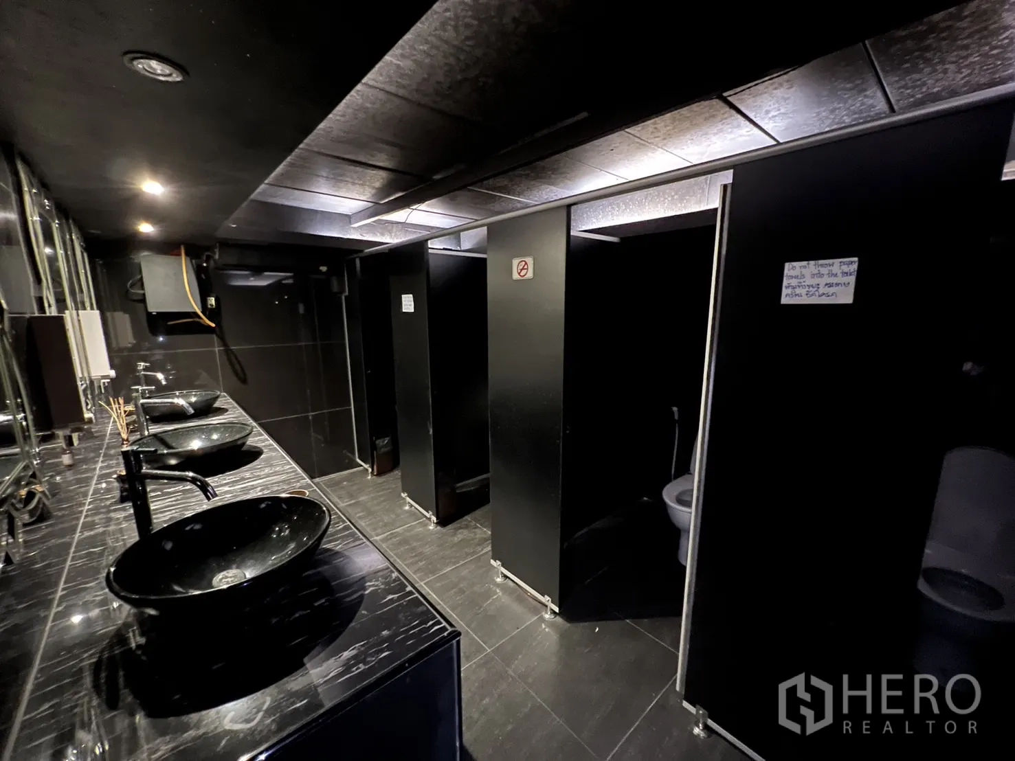 Retail Space for rent - Modern restroom with black vessel basins, mirrors, and toilet stalls.