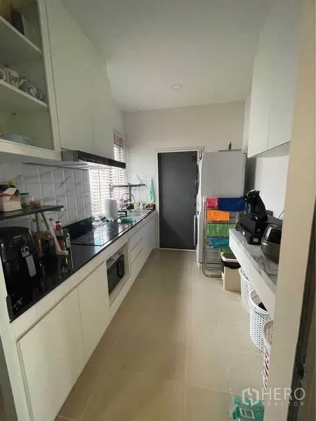 独立式住宅 出售在Lat Krabang, Bangkok - 走廊式厨房，白色橱柜、家电与后门。