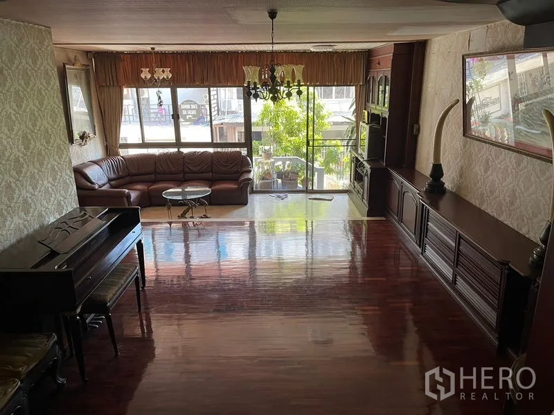 Home Office for rent in Watthana, Bangkok - Large living room with chandelier, glossy wooden floors and front windows.