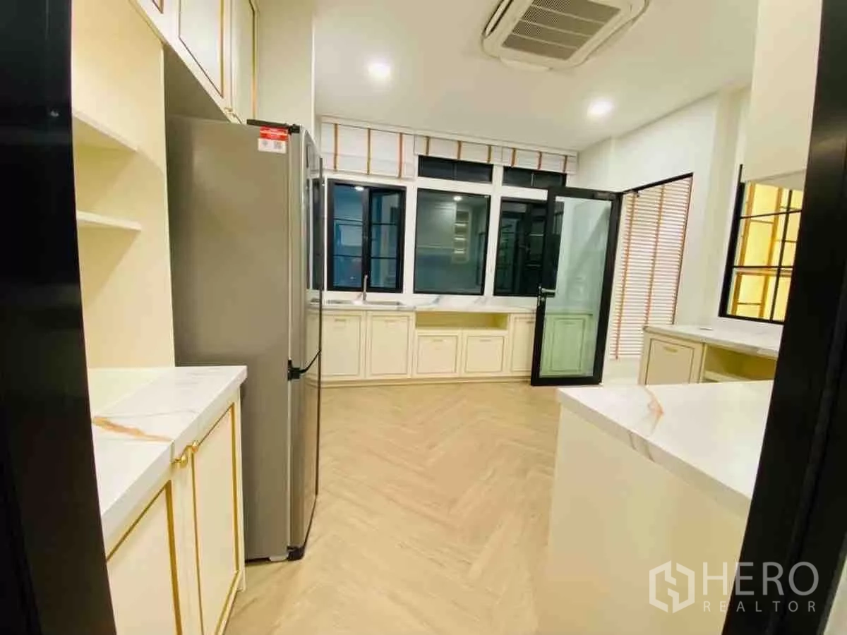 Detached House for rent or sale in Saphan Sung, Bangkok - Bright kitchen with white cabinets, herringbone floor and stainless fridge