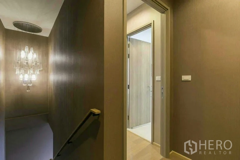 公寓 出租或出售在Watthana, Bangkok - 走廊与楼梯平台，悬挂当代吊灯，并连接浴室门。