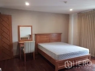 房间 出租在Pathum Wan, Bangkok - 明亮卧室，木质床架、梳妆台与落地窗帘。
