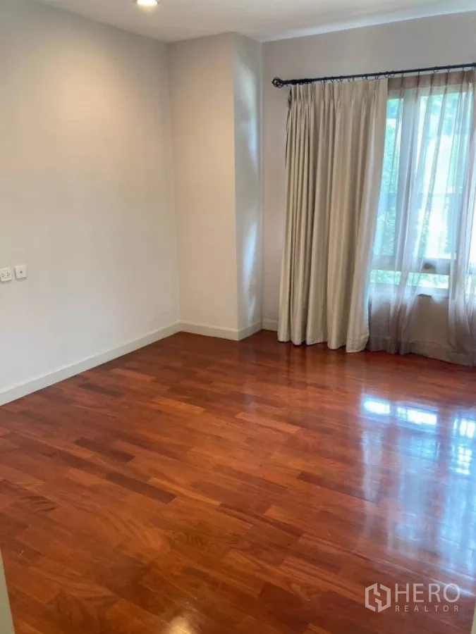Detached House for rent in Mueang Nonthaburi, Nonthaburi - Empty bedroom showcasing glossy hardwood floors and curtained window.
