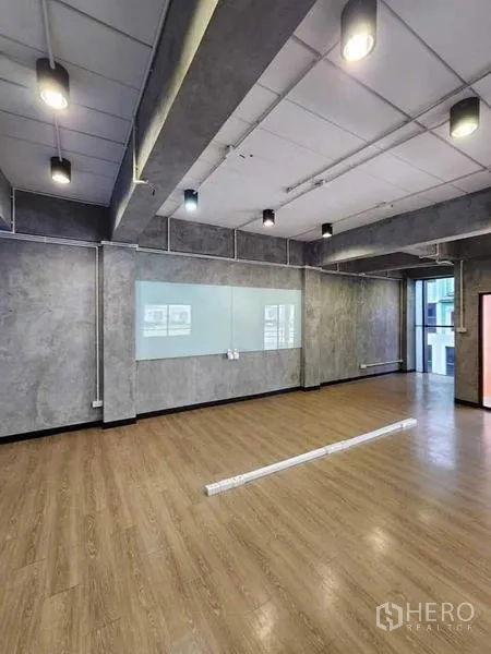 办公空间 出租或出售在Bueng Kum, Bangkok - 开放式办公区，木地板、玻璃白板、工业风顶灯与大窗户。
