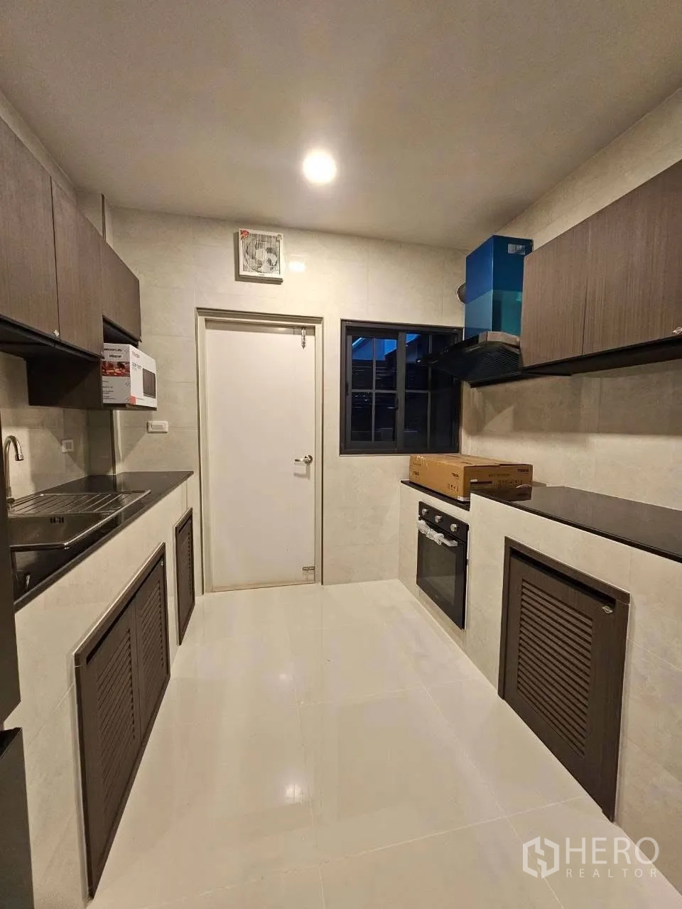 Detached House for rent or sale in Bang Phli, Samut Prakan - Bright galley kitchen with stone countertops, built-in oven, and upper cabinets.