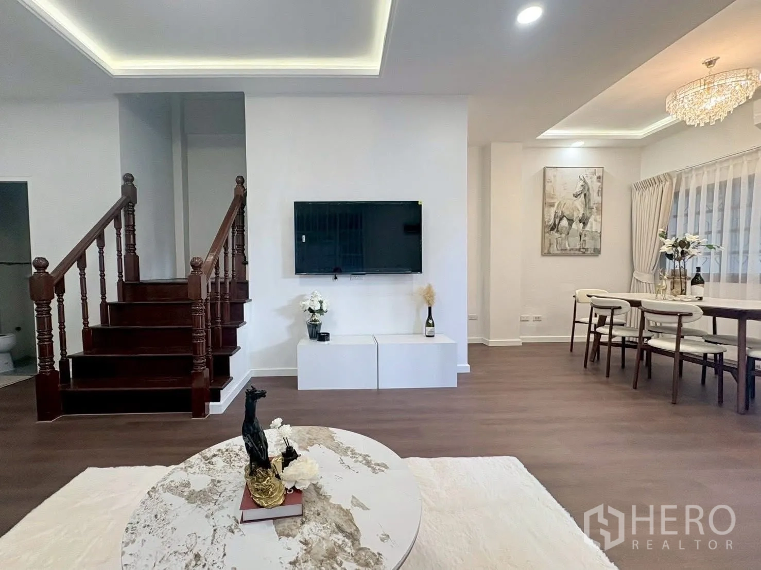 ทาวน์เฮาส์ for rent in Huai Khwang, Bangkok - โถงนั่งเล่นเชื่อมทานอาหาร ทีวีติดผนัง โคมไฟระย้า และบันไดไม้