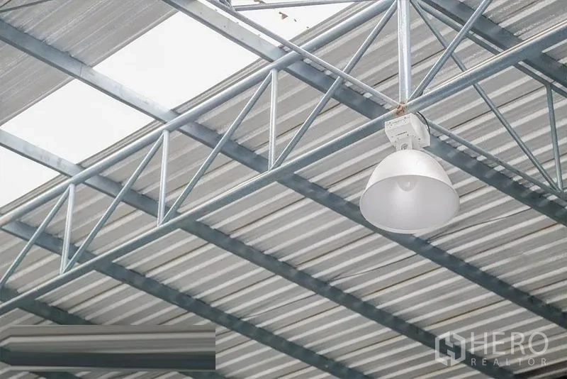 Warehouse for rent - Close-up of high-bay light fixture mounted on a steel truss ceiling.