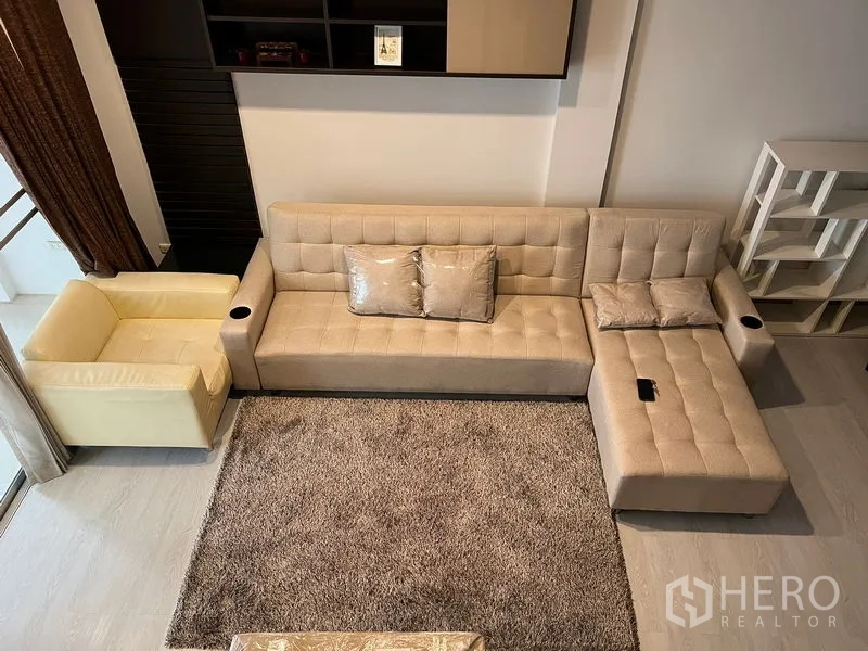 Townhouse for rent in Saphan Sung, Bangkok - Overhead view of a beige L-shaped sofa on a plush rug in the lounge.