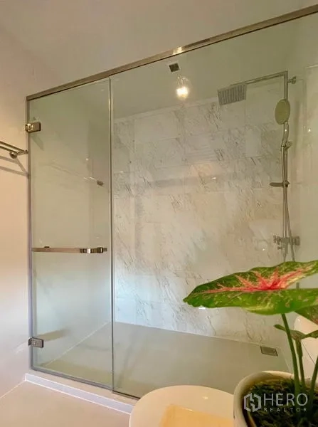 Condominium for rent or sale in Watthana, Bangkok - Close‑up of marble‑lined shower with glass enclosure, rain and handheld heads.