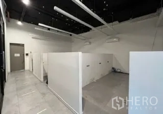 Retail Space for rent in Khlong Toei, Bangkok - Open retail interior with white partition walls, tiled floor and exposed black ceiling with linear lights.