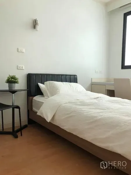 Condominium for rent in Watthana, Bangkok - Bright bedroom with a single bed, side table, window and compact study desk.