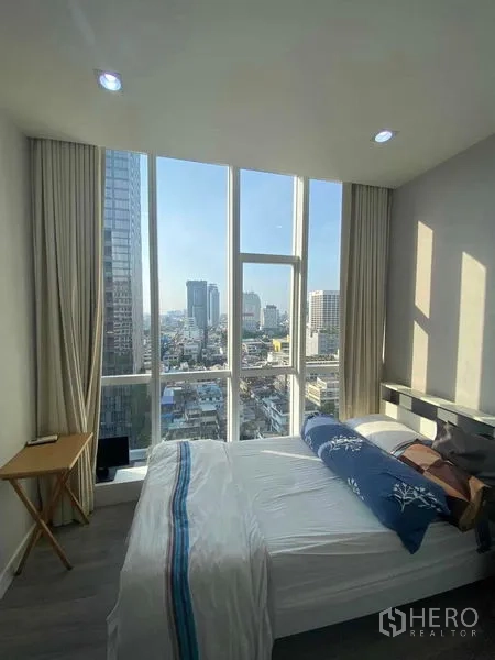 Condominium for rent or sale in Bang Rak, Bangkok - Bright bedroom with floor-to-ceiling windows and panoramic Bangkok skyline view.