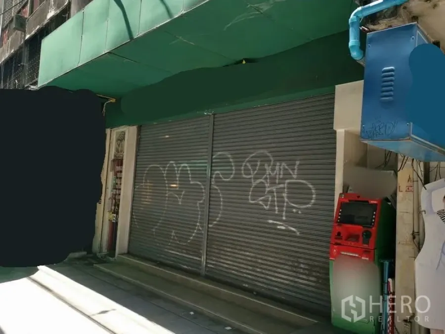 Shophouse for rent in Bangkok - Street-level shophouse frontage with green awning and closed metal roller shutters.