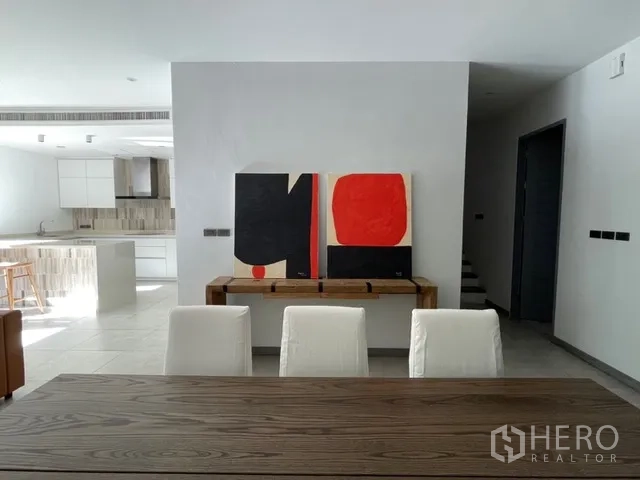 独栋房屋 for rent in Watthana, Bangkok - 餐区木桌，后方为现代厨房与装饰画。
