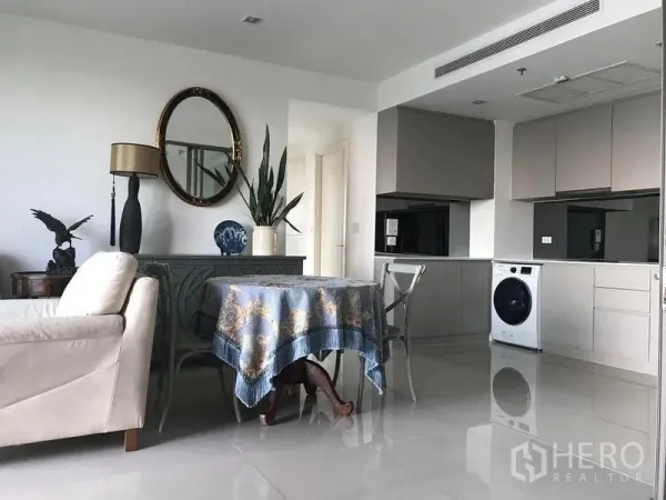 Condominium for rent in Bang Kho Laem, Bangkok - Living and dining space with sofa, round table, decorative mirror and open kitchen.