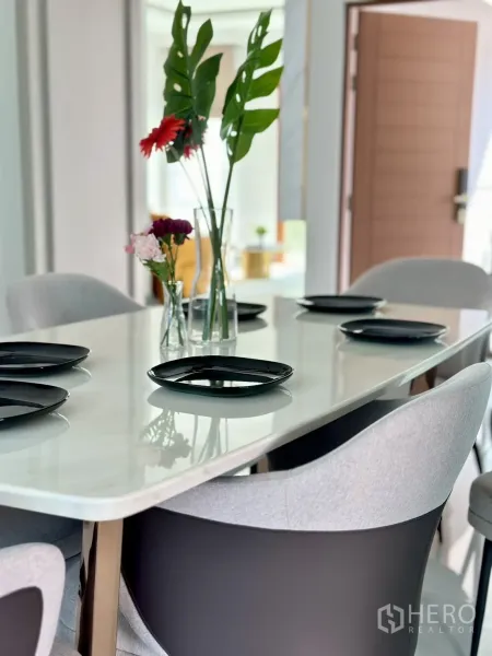 Detached House for rent or sale - Close-up of dining table set with black plates and vases holding tropical leaves and flowers.