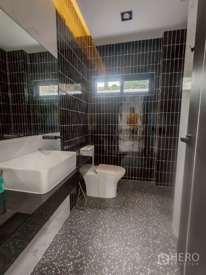 Detached House for rent in Wang Thonglang, Bangkok - Bathroom with vertical black tiles, square basin, and clerestory windows.
