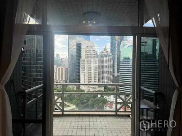 公寓 出租在Pathum Wan, Bangkok - 阳台通过落地玻璃俯瞰曼谷天际线与绿意景观。