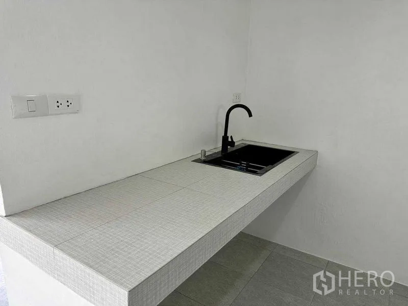 Office Space for rent or sale in Khlong Toei, Bangkok - Compact pantry with tiled countertop, black faucet and power outlets.