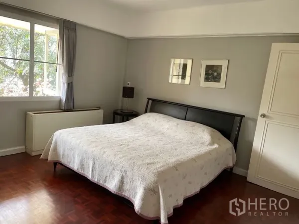 Condominium for rent in Watthana, Bangkok - Cozy master bedroom with large window, king bed and soft grey walls.