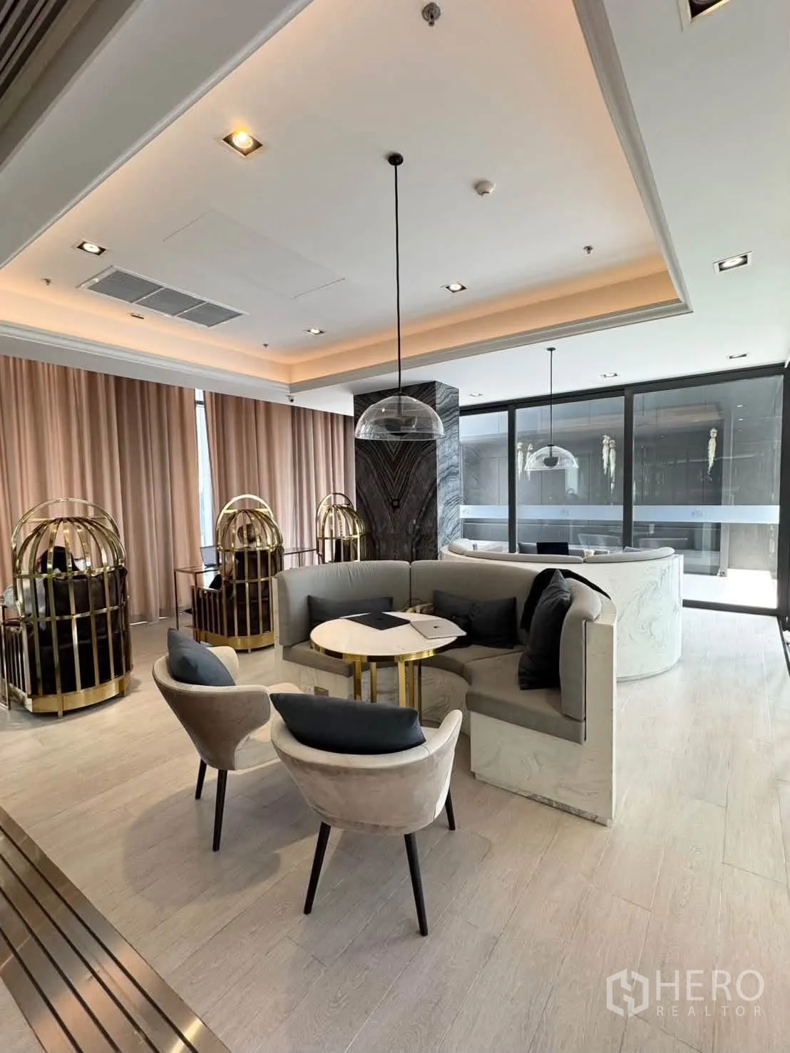 Condominium for rent in Pathum Wan, Bangkok - Cozy lounge area with curved sofa, pendant lights, and floor-to-ceiling curtains.