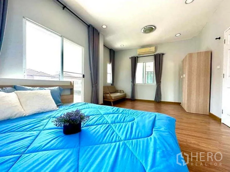 Detached House for rent in Lat Krabang, Bangkok - Spacious master bedroom with blue duvet, multiple windows and air conditioner.