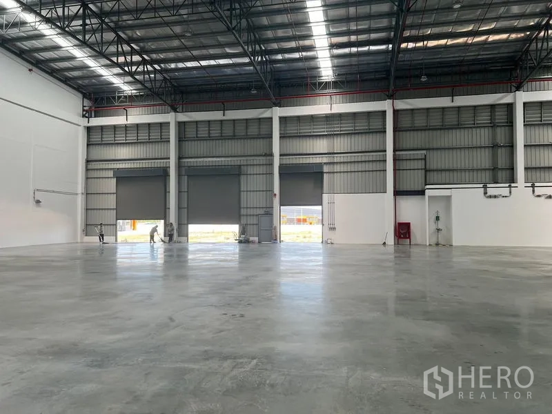 工厂 出租在Bang Pakong, Chachoengsao - 仓库内多扇卷帘门通向场地，地面平整，屋架高挑。