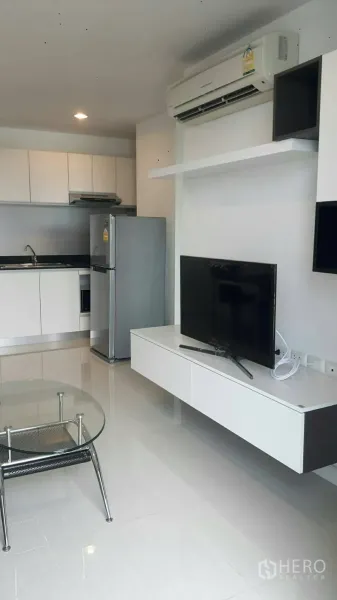 Condominium for rent in Phaya Thai, Bangkok - Open-plan living room with TV console facing a compact kitchenette and stainless-steel refrigerator.