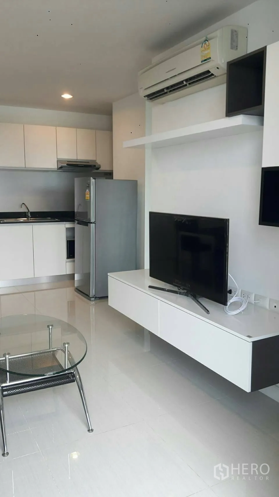 Condominium for rent in Phaya Thai, Bangkok - Open-plan living room with TV console facing a compact kitchenette and stainless-steel refrigerator.