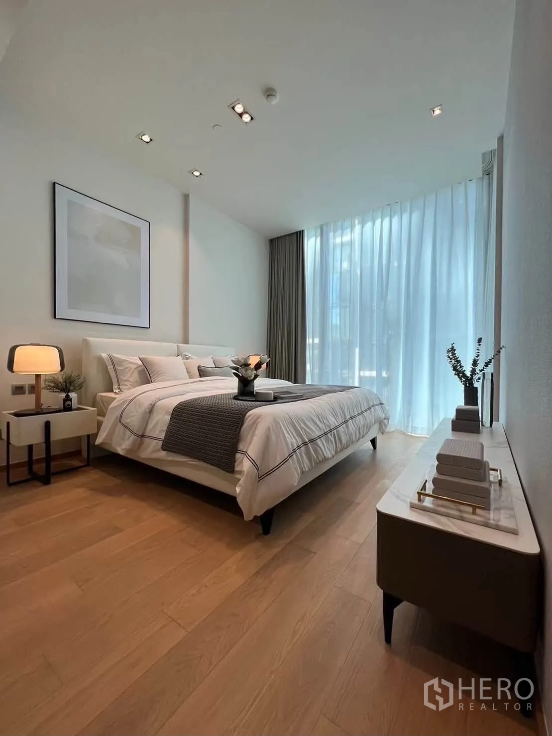 Condominium for rent in Pathum Wan, Bangkok - Serene bedroom with double bed, bedside lamp, dresser, and sheer curtains.
