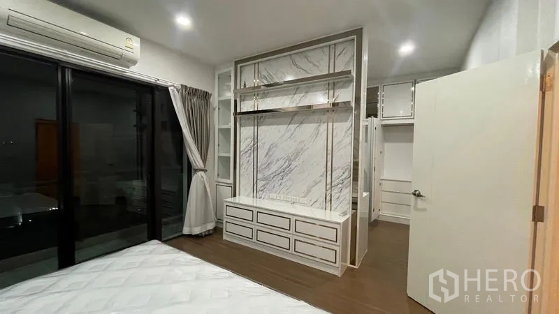 บ้าน ให้เช่าหรือขายในPrawet, Bangkok - ห้องนอนพร้อมผนังทีวีลายหินอ่อน ประตูบานเลื่อนออกระเบียง และพื้นไม้