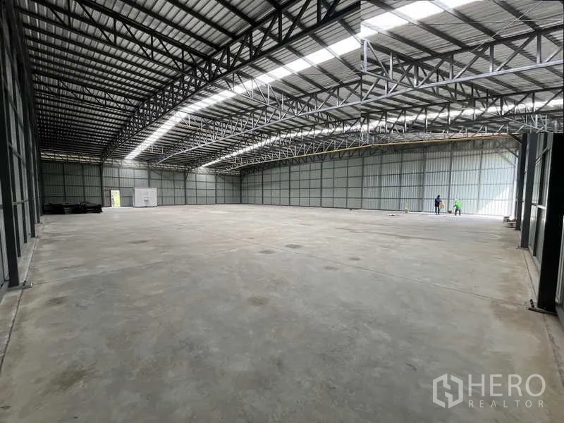 Warehouse for rent or sale in Pak Kret, Nonthaburi - Open-plan warehouse floor with wide loading access at the far end beneath steel framing.
