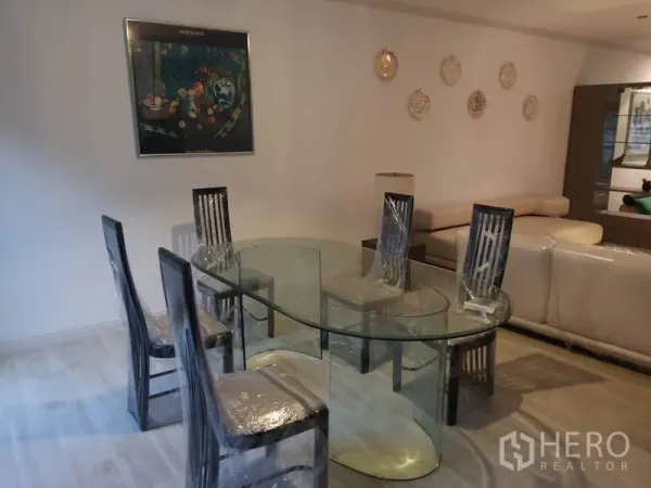 联排别墅 出租在Khlong Toei, Bangkok - 餐区有椭圆玻璃餐桌、六把椅子与墙面装饰