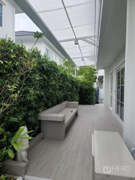 Detached House for rent in Bang Phli, Samut Prakan - Covered side terrace with built‑in bench seating, tiled floor and privacy hedge.