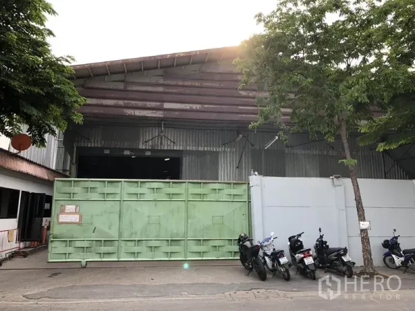 คลังสินค้า ให้เช่าในLak Si, Bangkok - ภายนอกโกดังโครงเหล็กในเขตหลักสี่ กรุงเทพฯ พร้อมประตูบานเลื่อนสีเขียวขนาดใหญ่และหน้ากว้างติดถนน