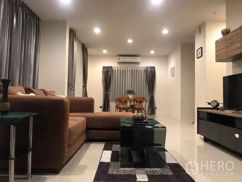 Detached House for rent in Bang Kapi, Bangkok - Open-plan living and dining area with L-shaped sofa, air conditioner and recessed lighting.