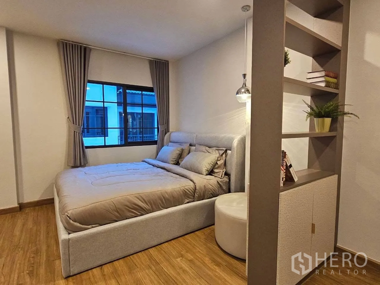 Detached House for rent or sale in Bang Phli, Samut Prakan - Bedroom corner showing bed beside decorative shelving and a pendant light.