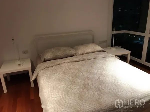 Condominium for rent in Watthana, Bangkok - Bright guest bedroom with corner windows and a white bed frame.