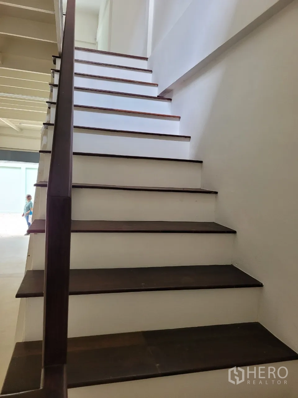 Shophouse for rent in Khlong Toei, Bangkok - Staircase rising to the upper level, looking toward bright front windows.