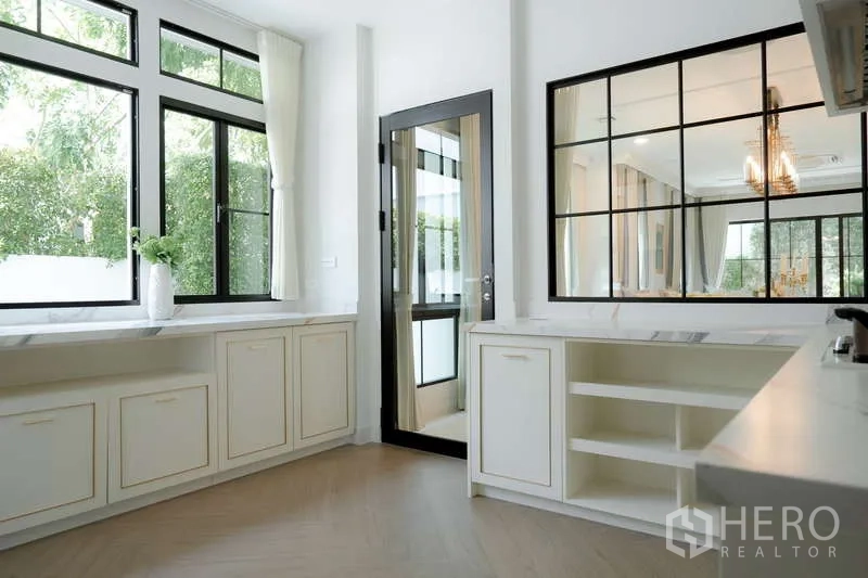Detached House for rent or sale in Saphan Sung, Bangkok - Kitchen second angle showing large windows, rear door and generous counter space.
