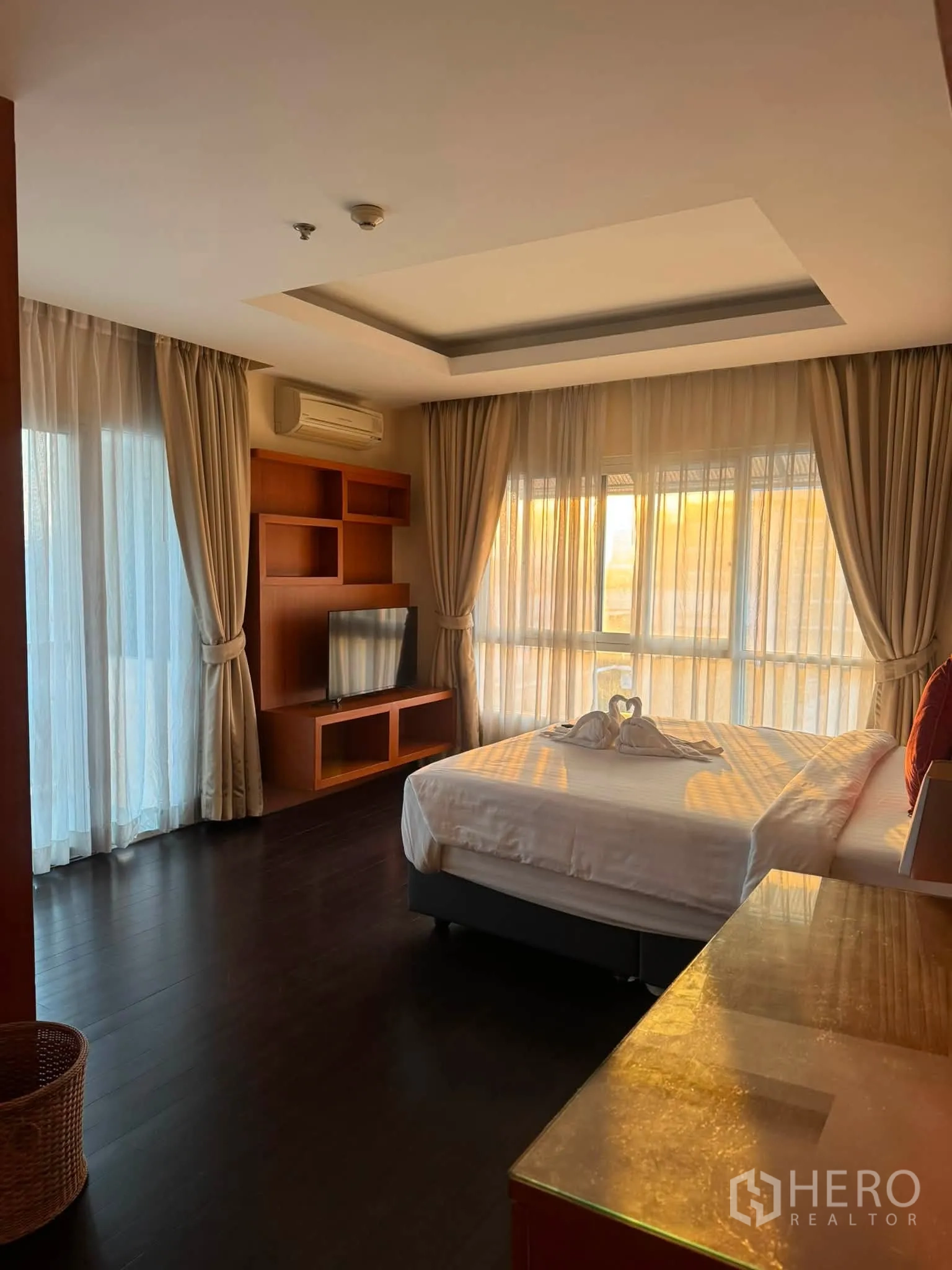 公寓 for rent in Khlong Toei, Bangkok - 卧室采光充足，设有大窗与薄纱窗帘、木质电视柜与深色木地板。