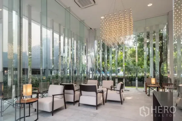 Condominium for rent in Khlong Toei, Bangkok - Elegant residents’ lounge with full‑height glass walls, armchairs and a crystal chandelier.