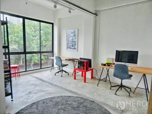 Home Office for rent or sale in Din Daeng, Bangkok - Bright open-plan workspace with large windows, concrete floor and minimalist desks overlooking greenery.
