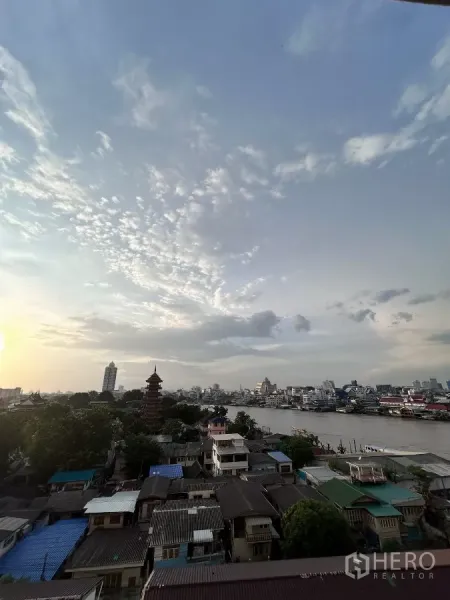 คอนโด ให้เช่าในKhlong San, Bangkok - ทิวทัศน์แม่น้ำเจ้าพระยาและสกายไลน์ยามเย็น พร้อมเจดีย์และชุมชนริมน้ำ