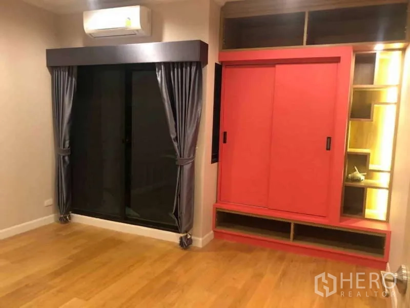 Detached House for rent or sale in Prawet, Bangkok - Empty bedroom with red built-in cabinet, grey curtains and wood floor.