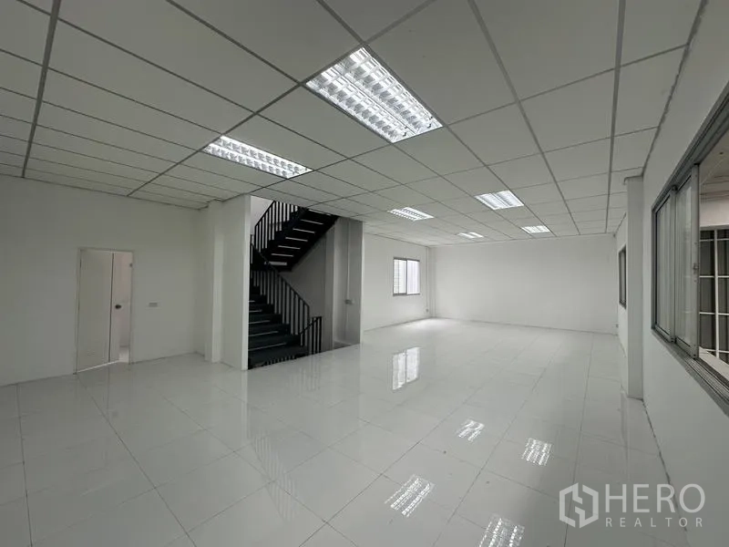 工厂 出租在Khlong Luang, Pathum Thani - 第二处办公室空间，带楼梯与明亮灯光、白色地砖。
