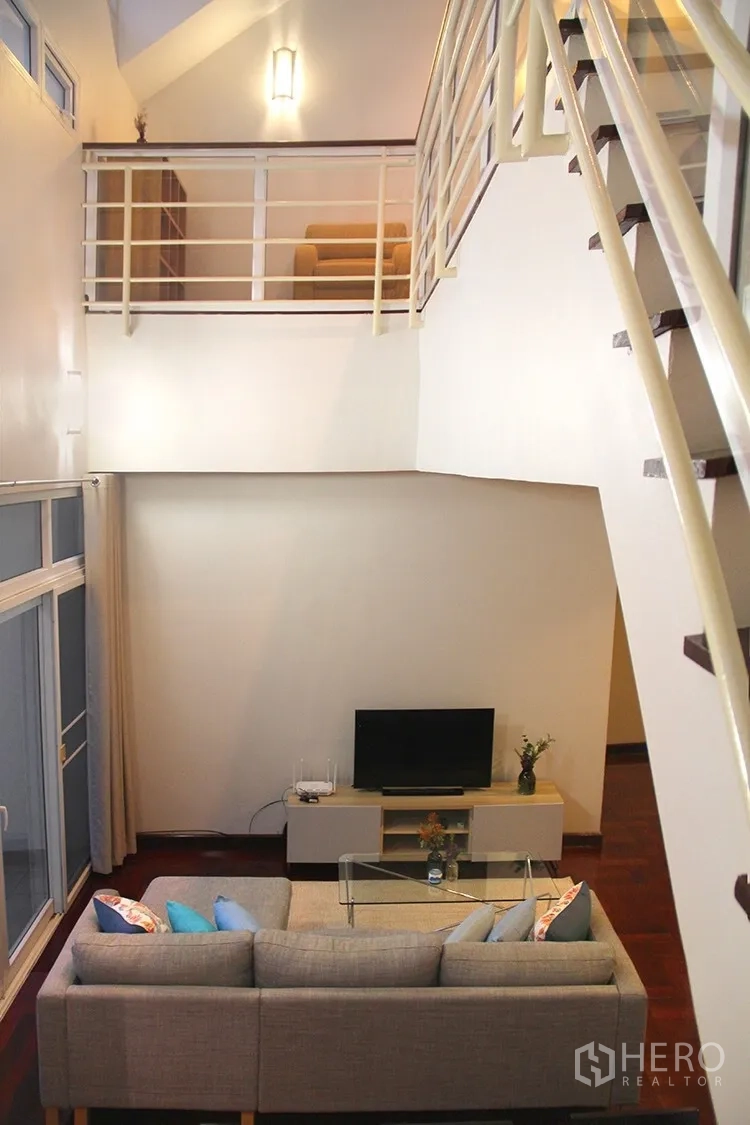 Apartment for rent in Khlong Toei, Bangkok - Loft-style living room with mezzanine, TV console and gray sofa