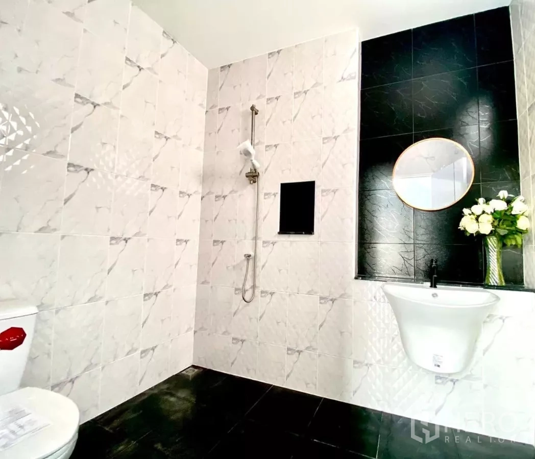 Factory for rent or sale in Bang Bua Thong, Nonthaburi - Fully tiled bathroom with shower, toilet and round-mirror vanity.
