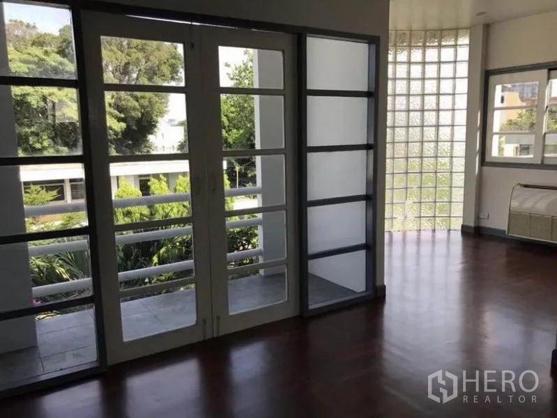 Townhouse for rent in Suan Luang, Bangkok - Large room with floor-to-ceiling French doors, a curved glass-block wall and garden views.